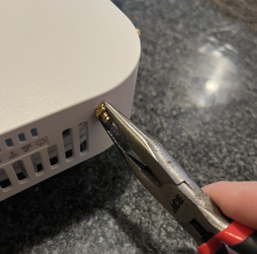 Using a pliers to tighten the nut around the SMA connector to keep it in place.